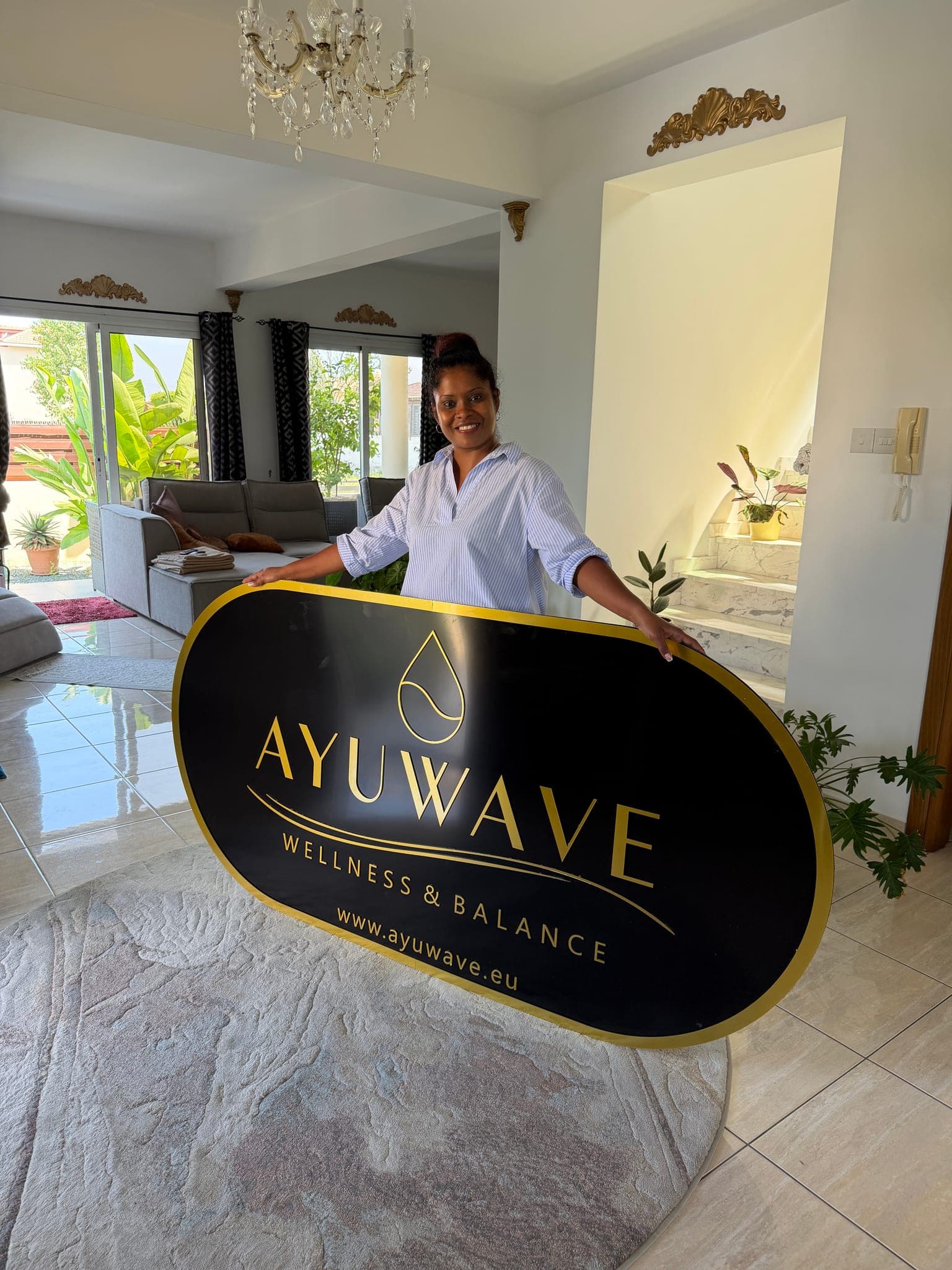 Hiranthi, the AYUWAVE therapist, holding the studio sign in the lobby